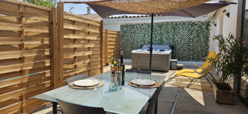 Terrasse Mi Casa Es Su Casa avec table à manger, bain à remous, chaise longue, clôture en bois et parasol