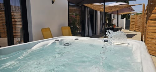 Jacuzzi bouillonnant sur la terrasse du Loft, Mi Casa Es Su Casa, Villemoustaussou avec chaises longues et vue sur le jardin