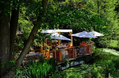 Wooden terrace with umbrellas nestled in lush greenery at Le Paradis de Lucile, La Roche Guyon