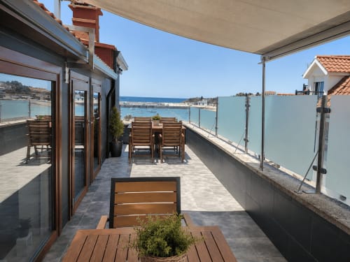 Terraza frente al mar en Holibai Nigran con vistas oceánicas, muebles de madera y barandillas de cristal con vista a Playa America
