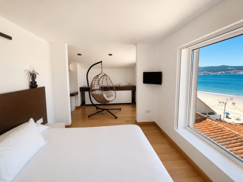 Moderno dormitorio dúplex frente al mar en Nigrán con vistas al océano, silla colgante y acceso directo a la playa
