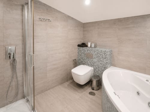 Baño moderno en apartamento Holibai, Nigrán, con ducha a ras de suelo, inodoro suspendido y bañera con mosaico