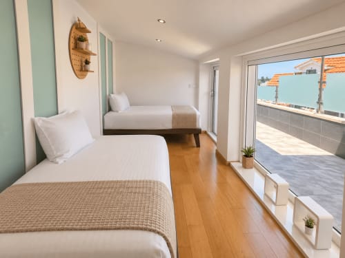 Dormitorio de dúplex frente al mar en Nigrán con dos camas, suelos de madera, terraza con vistas al mar y decoración contemporánea