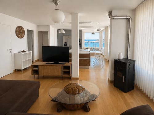 Salón moderno de dúplex en Nigrán con vistas al mar, suelos de madera, TV y océano visible desde grandes ventanales
