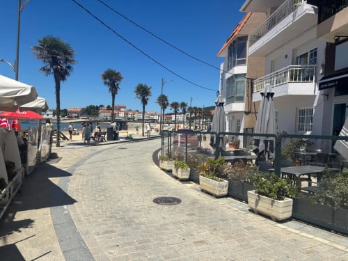 Paseo marítimo de Holibai Nigrán con palmeras, edificios costeros y acceso a la playa en Playa América