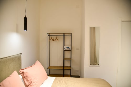 Camera da letto moderna a Onde Del Mare B&B Napoli con cuscini rosa, armadio in metallo nero e lampade a sospensione