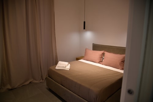 Camera da letto moderna e doppia presso Onde Del Mare a Napoli con cuscini color corallo, illuminazione calda e design contemporaneo