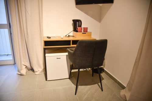 Spazio di lavoro moderno con scrivania in legno, sedia nera e frigobar nella guest house Onde Del Mare a Napoli