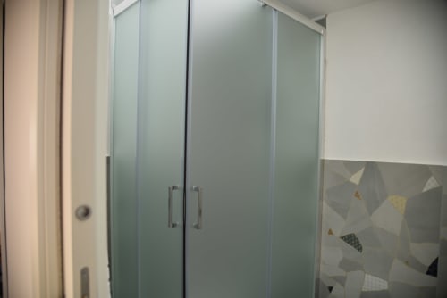 Moderno box doccia in vetro satinato con parete di piastrelle geometriche nella bathroom dell'hotel di Napoli