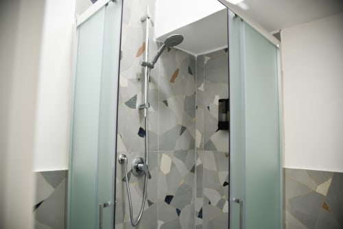 Doccia moderna con box in vetro e design geometrico delle piastrelle presso l'hotel Onde Del Mare, Napoli