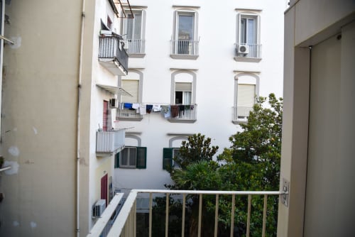 Cortile di palazzo bianco con balconate, persiane verdi e piante tropicali presso l'Onde Del Mare B&B a Napoli