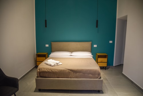 Moderna Suite Deluxe al Onde Del Mare di Napoli con parete accent turchese, comodini in legno e vista giardino