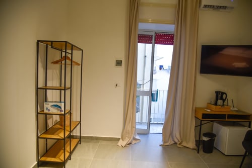 Camera Matrimoniale Deluxe presso Onde Del Mare, Napoli - Camera da letto moderna con attaccapanni, scrivania, TV, porte con balcone e vista sul giardino