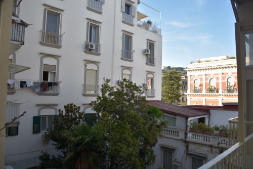 Vista del cortile giardino di Napoli dalla camera deluxe dell'hotel Onde Del Mare, con edifici bianchi e palazzo arancione