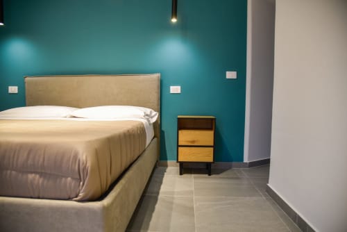 Camera moderna a Onde Del Mare, Napoli con parete in turchese, letto in tessuto beige, comodino in legno e piastrelle