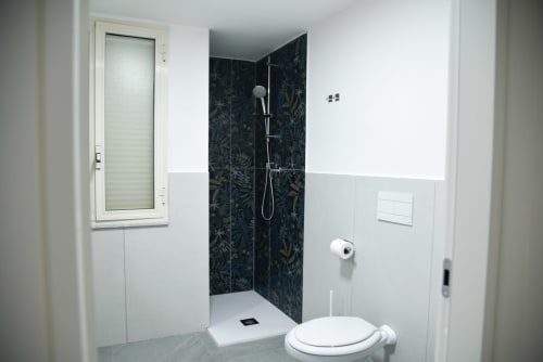 Bagno moderno nel B&B Onde Del Mare di Napoli con box doccia a motivi scuri, sanitari bianchi e pavimento in piastrelle