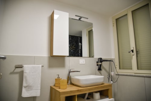 Bagno moderno nella struttura B&B di Napoli con vanity in legno, lavabo bianco a coppa e specchio con illuminazione integrata