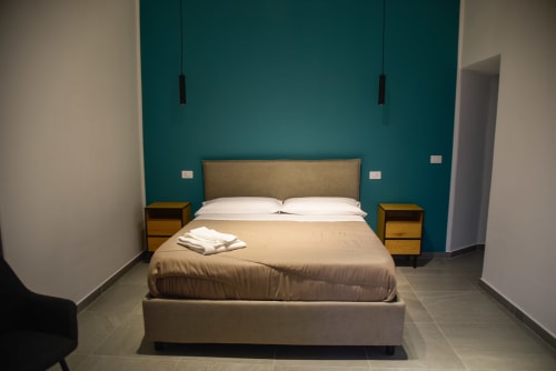 Camera Doppia Deluxe al Onde Del Mare di Napoli con parete azzurra, comodini in legno e pavimento in piastrelle