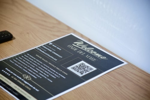 Biglietto benvenuto WiFi dell'appartamento Onde Del Mare a Napoli con codice QR e dettagli di connessione su tavolo in legno