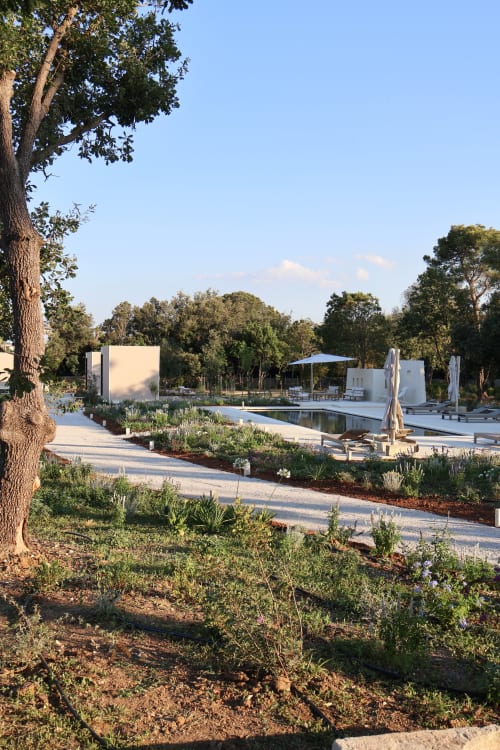Area piscina di Quercia Private Nature Retreat con lettini, ombrelloni e moderni padiglioni bianchi circondati da paesaggio mediterraneo