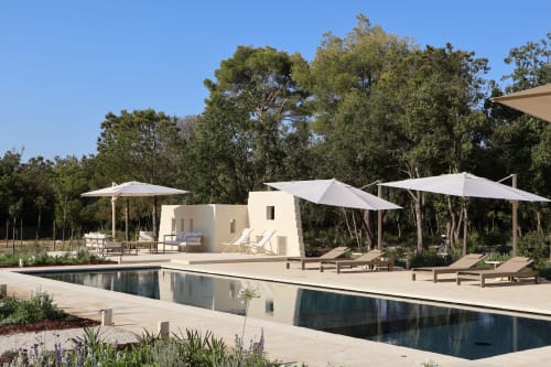 Area piscina della Quercia Private Nature Retreat con lettini, ombrelloni bianchi e architettura moderna circondata da alberi
