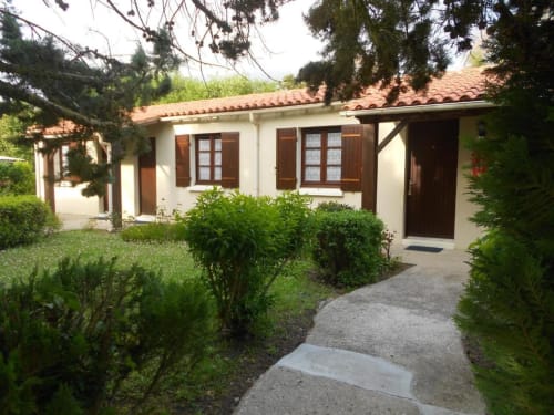Charming cottage at Domaine de la Gare with terracotta roof, white walls, wooden shutters, and lush garden in