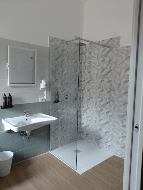 Bagno accessibile al Makasa B&B, Villapiana. Moderno box doccia con piastrelle a motivo foglie, lavabo bianco e legno