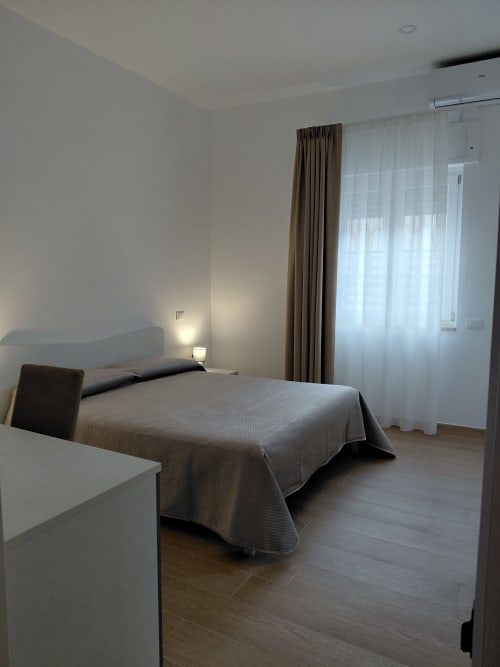 Camera accessibile al Makasa B&B di Villapiana con letto, scrivania, TV e vista sul giardino attraverso tende trasparenti
