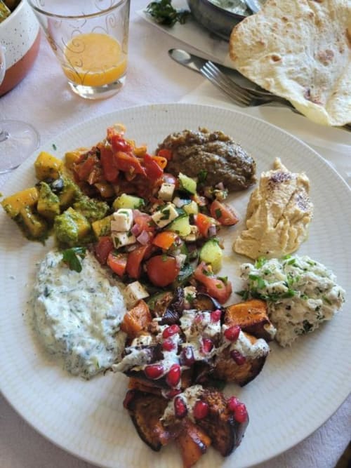 Assiette petit-déjeuner au Domaine de la Gare M avec dips mezze, viande grillée, salade fraîche, pommes de terre rôties et pain