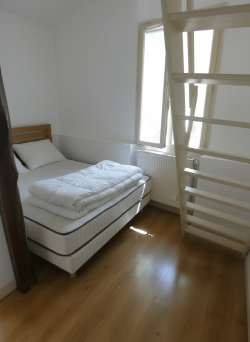 Chambre lumineuse avec lit simple, draps blancs, parquet, porte-fenêtre avec volets ouvrant sur le jardin, villa Sci Ludji