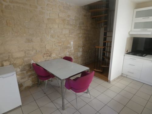 Salle à manger de la villa Maison Jardin Triplex avec table grise, chaises violettes, murs de brique et kitchenette à Nanterre.