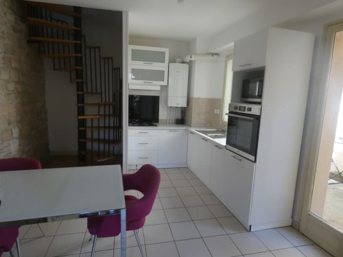 Cuisine et salle à manger modernes de la villa Sci Ludji avec armoires blanches, appareils inox et chaises bordeaux
