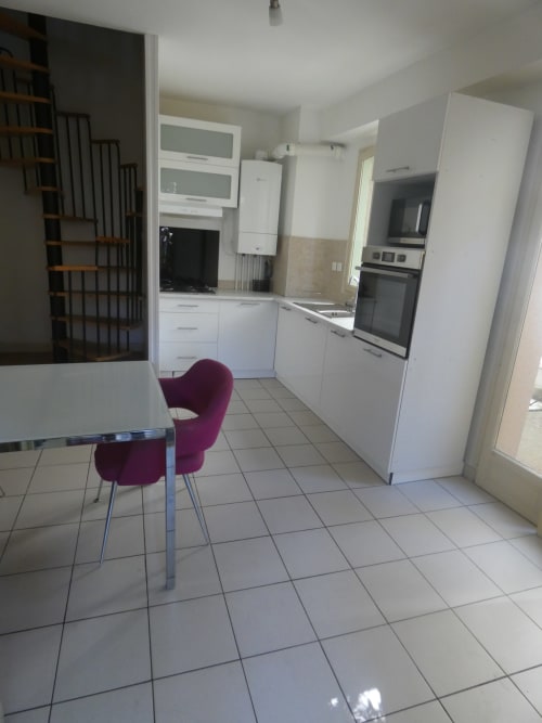 Cuisine moderne aux meubles blancs, coin repas avec chaise bordeaux à la villa Sci Ludji à Nanterre