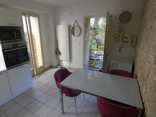 Salle à manger moderne de la villa Sci Ludji à Nanterre avec table blanche, chaises bordeaux et portes donnant sur le jardin