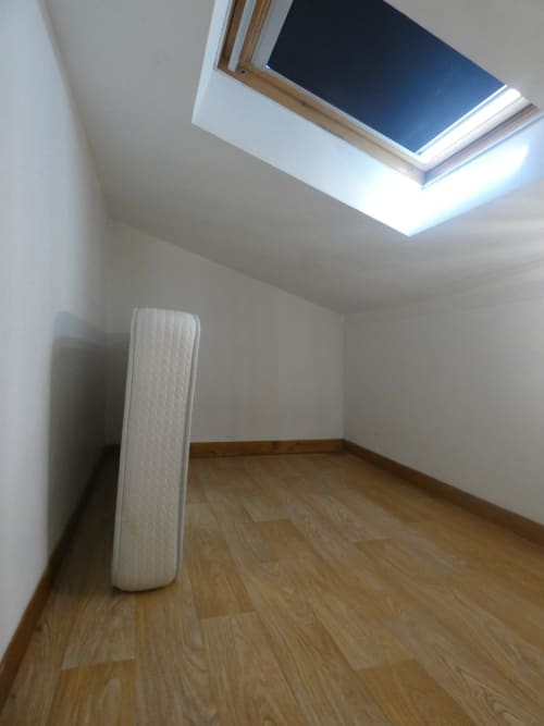 Pièce mansardée vide avec puits de lumière, parquet en bois et murs blancs à la villa Sci Ludji à Nanterre