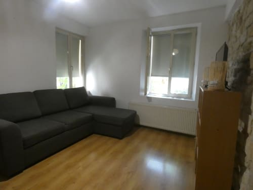 Salon moderne avec canapé sectionnel noir, parquet bois et vue sur jardin à la villa Sci Ludji à Nanterre