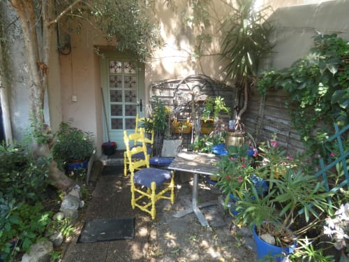 Charmante terrasse jardin de la villa Sci Ludji à Nanterre avec chaise jaune, table à manger, pergola et verdure luxuriante