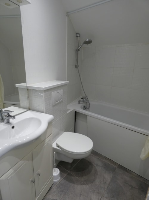 Salle de bains moderne de l'appartement Sci Ludji à Nanterre avec lavabo blanc, toilettes, baignoire et douche