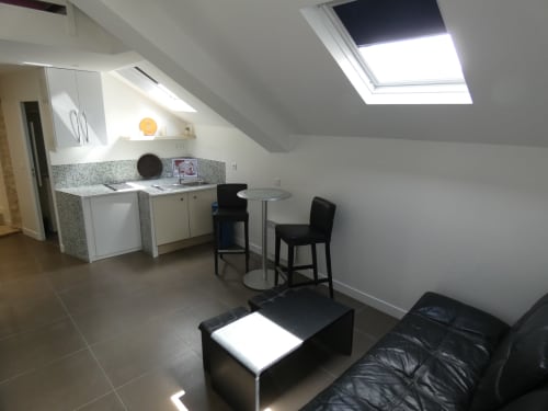 Loft moderne à Nanterre avec kitchenette, coin repas, mobilier noir et puits de lumière