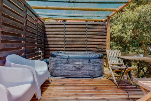 Deck da cabana de glamping com banheira de hidromassagem, espreguiçadeiras brancas e paredes cobertas de hera na Arrabia Guest Houses, Castelo de Paiva