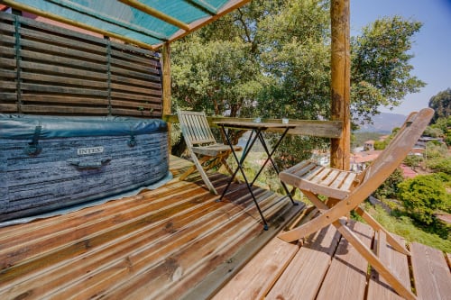 Deck de madeira com banheira de hidromassagem, espreguiçadeira e mesa em Arrabia Guest Houses Glamping, Castelo de Paiva