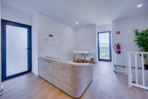 Sala de estar integrada moderna da Casa Bernardo em Arrabia Guest Houses, com sofá cinzento, mesa de jantar e vistas para o rio