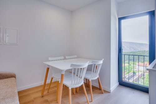 Área de jantar moderna com mesa e cadeiras brancas com vista para montanhas e rio na Glamping Arrabia Guest Houses, Casa