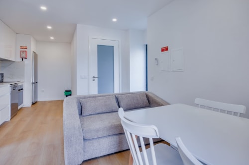 Estúdio moderno na Arrabia Guest Houses com sofá cinzento, mesa de jantar, kitchenette e portas azuis em Castelo