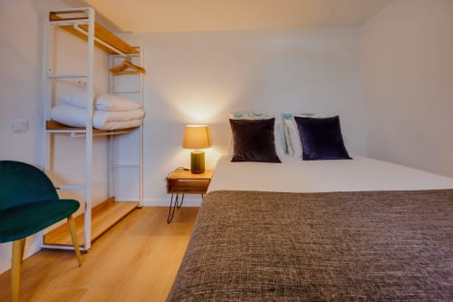 Quarto Casa Bernardo na Arrabia Guest Houses com cama queen, beliche no sótão, criado de madeira, luminária e poltrona verde em Castelo