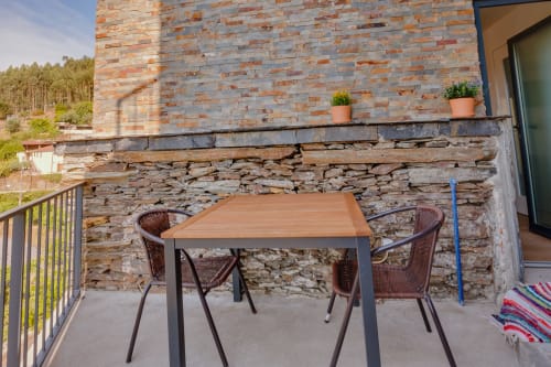 Pátio externo com mesa de madeira e cadeiras marrom na Arrabia Guest Houses em Castelo de Paiva, Portugal
