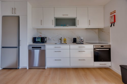 Cozinha moderna nas Casas de Hóspedes Arrabia em Castelo de Paiva com armários brancos, eletrodomésticos em aço inoxidável e mármore