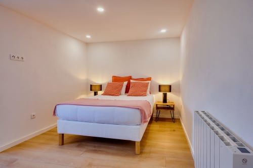 Quarto moderno na Arrabia Guest Houses com cama de casal, almofadas laranja, pisos de madeira e iluminação ambiente em Castelo de