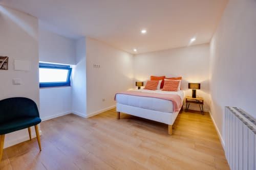 Quarto moderno na Arrabia Guest Houses em Castelo de Paiva com cama de casal, detalhes em laranja, piso de madeira e moldura azul