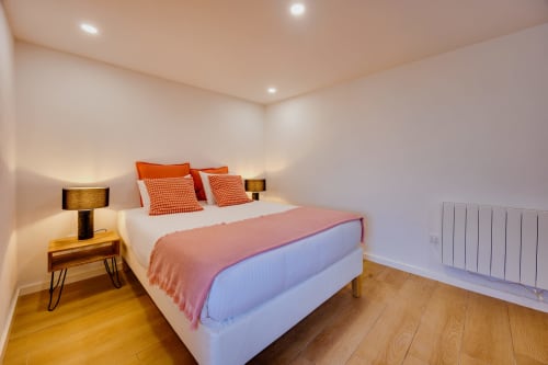 Quarto moderno em Arrabia Guest Houses com detalhes em laranja, piso em madeira e iluminação ambiente em Castelo de Paiva